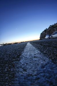 Surface level of road against clear blue sky