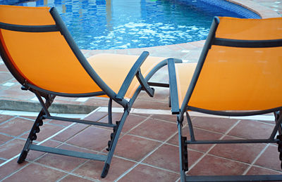 Empty chairs by swimming pool in sea