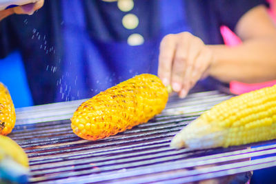 Midsection of man roasting corns