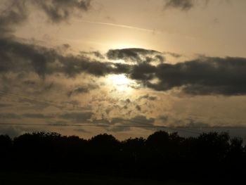 Silhouette of trees against cloudy sky