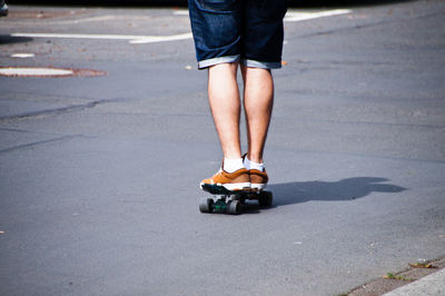 Low section of man skateboarding on road