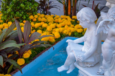 Statue of people on yellow flowering plant