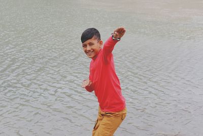 Portrait of boy gesturing while standing in lake