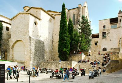 People by motor scooters parked against old buildings