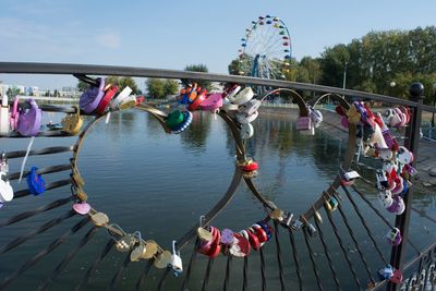 Padlocks on bridge over river against sky