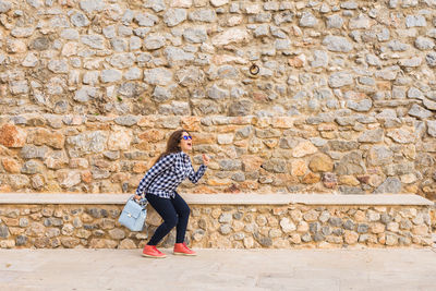 Full length of woman standing against wall