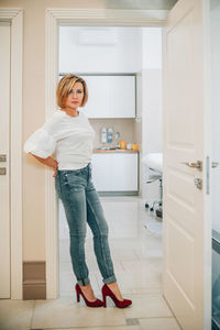 Portrait of a beautiful slender woman in full growth in the doorway of a bright medical office