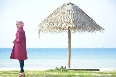 Beautiful woman with thatched roof parasol at beach