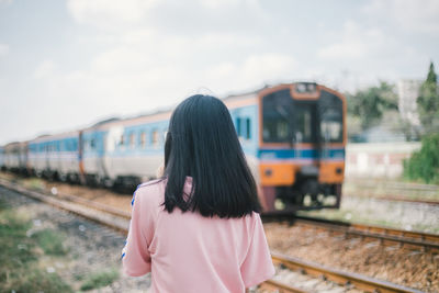 Rear view of woman with train at railroad station platform