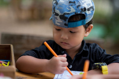 Portrait of boy holding eyeglasses on table