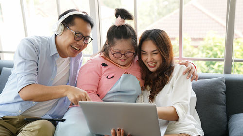 Woman using phone while sitting on laptop