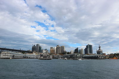 Sea by buildings against sky in city