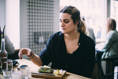 Young woman looking away while sitting on table