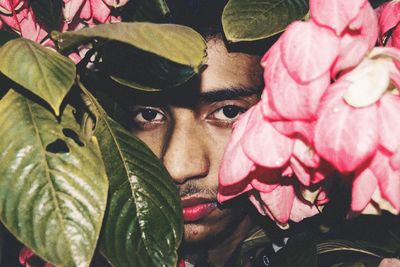 Portrait of man amidst pink flowers and green leaves