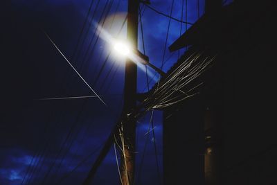 Low angle view of illuminated cables against sky at night