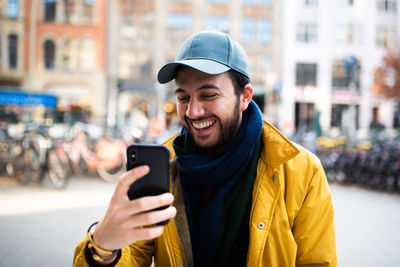 Happy young man using mobile phone in city