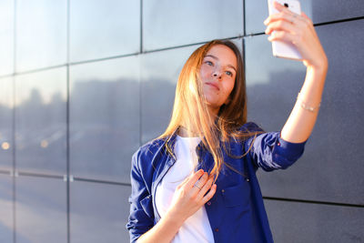 Portrait of young woman standing against wall