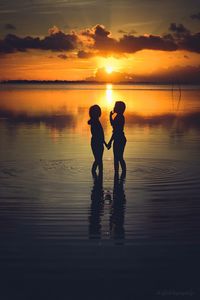 Silhouette children on beach at sunset