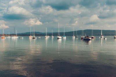 Sailboats moored on sea against sky