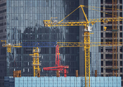 Crane at construction site against buildings in city