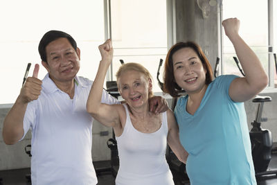 Portrait of smiling friends gesturing while standing in gym