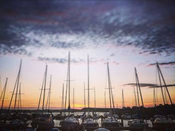 Sailboats moored at harbor against sky during sunset