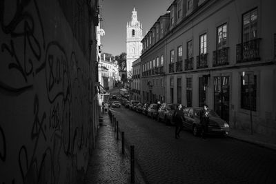 Women and cars on street amidst buildings