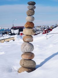 Stack of stones on snow covered land against sky