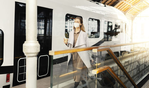 Woman wearing mask walking by train