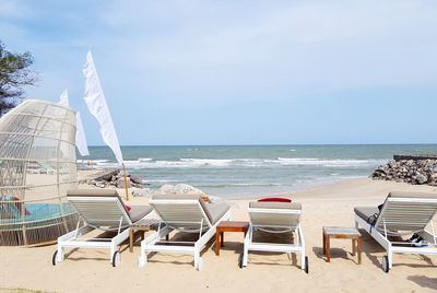 View deck chairs at beach against sky