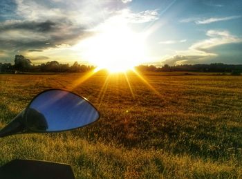 Scenic view of grassy field against sky at sunset