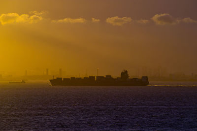 Ship in sea against sky during sunset