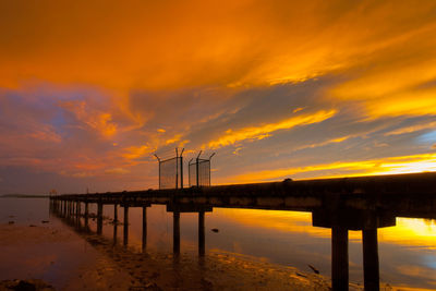 Pier over sea against romantic sky at sunset