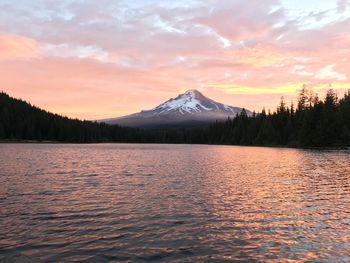 Scenic view of lake by snowcapped mountains against sky during sunset