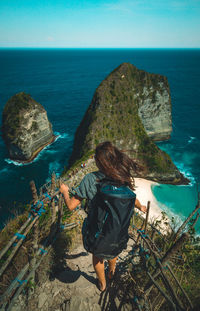 Rear view of woman on rock by sea