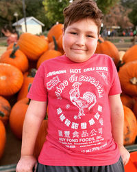 Portrait of smiling boy with pumpkins standing outdoors