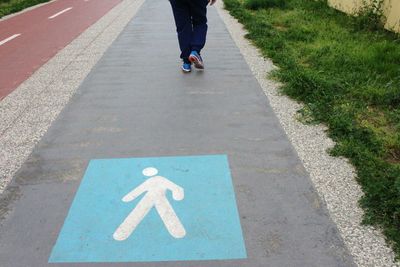 Low section of man walking on pedestrian walkway