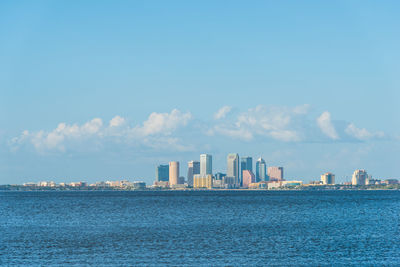 Sea by modern buildings against sky in city