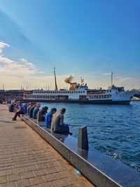 People on pier at sea against sky