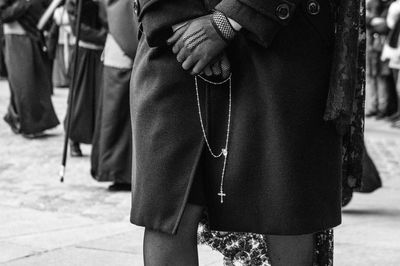 Midsection of woman holding praying beads while standing on street