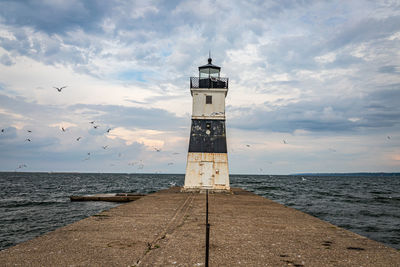 Lighthouse by sea against sky