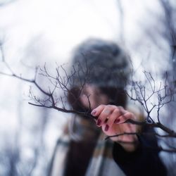 Woman holding branch while standing outdoors