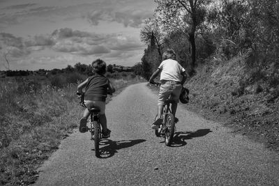 Rear view of people riding bicycle on road