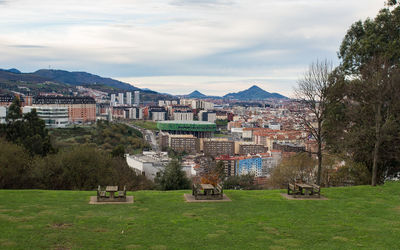 Scenic view of field by buildings against sky