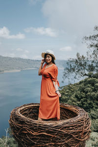 Portrait of smiling young woman standing against sky