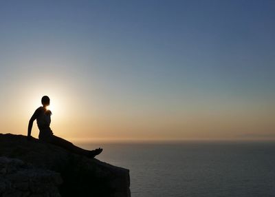 Silhouette of man looking at sea against sky