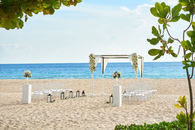 Chairs on beach by sea against sky