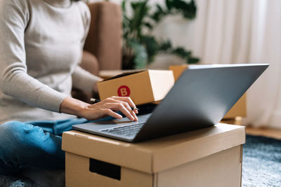 Midsection of woman using laptop at table