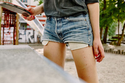 Low section of young woman using mobile phone