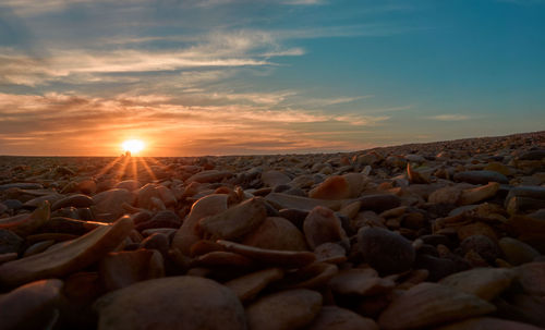 Rocks on beach against sky during sunset